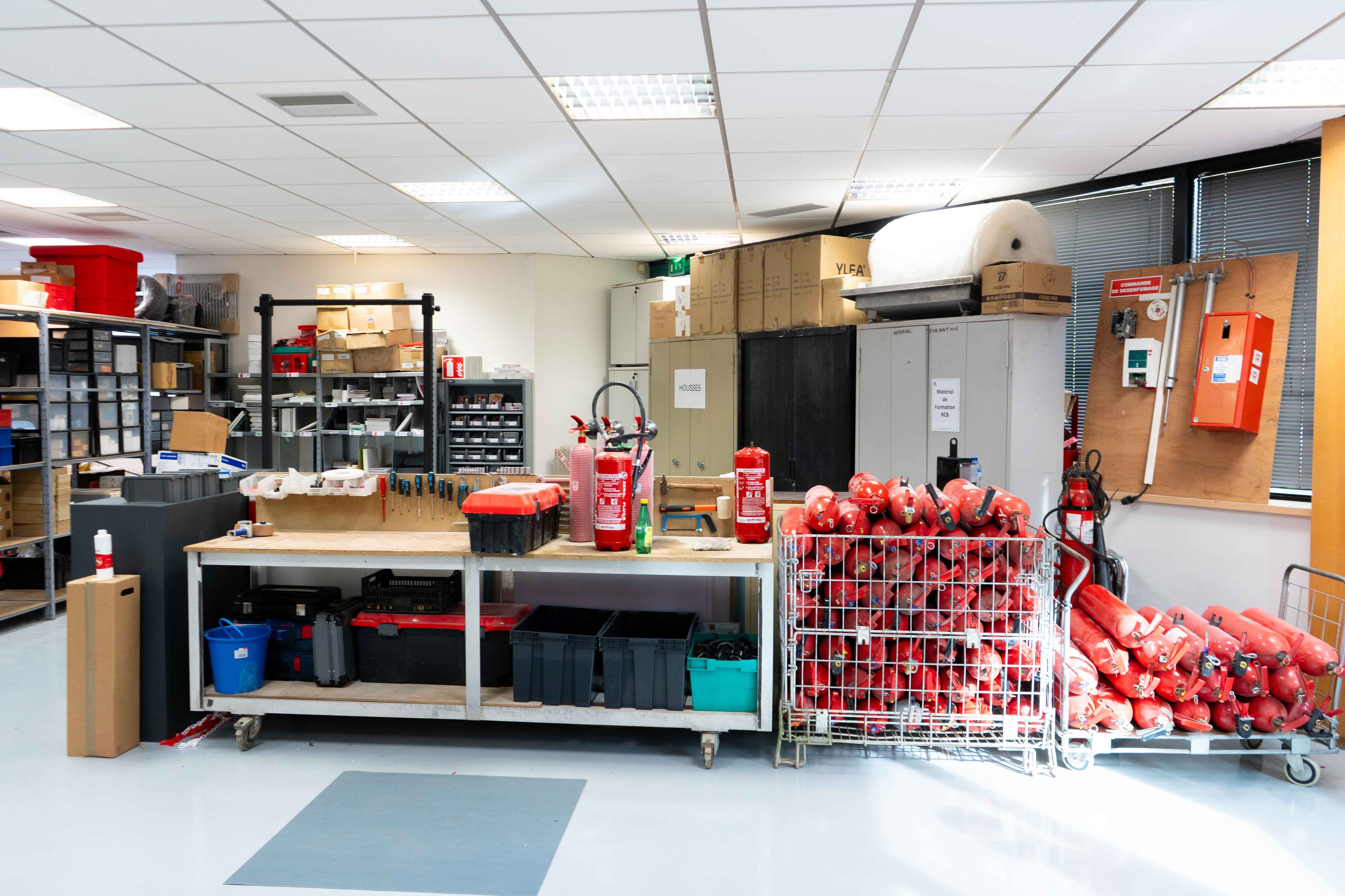 Atelier IP2S avec stock d'extincteurs et établi de maintenance