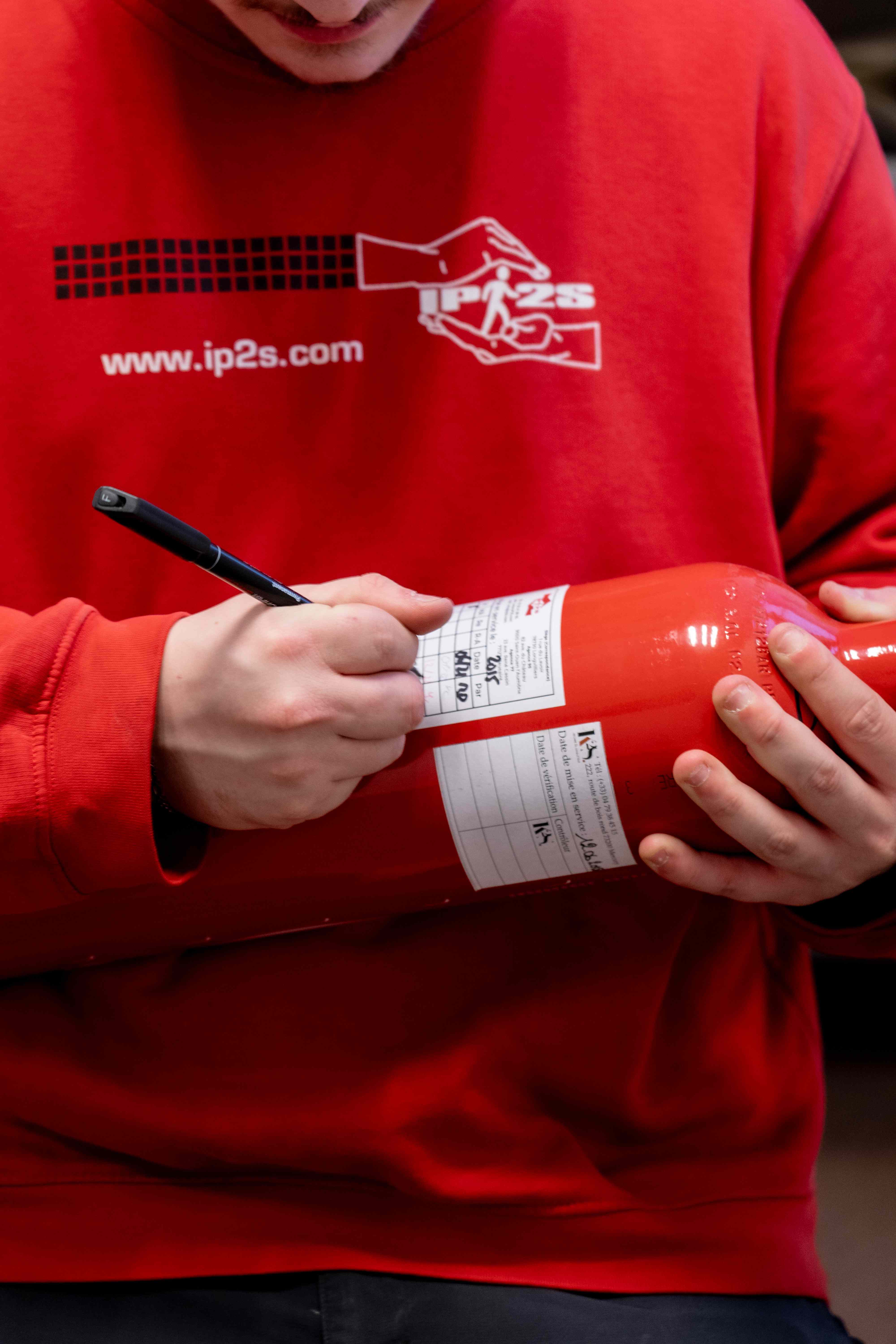 Technicien remplissant la fiche de suivi d'un extincteur