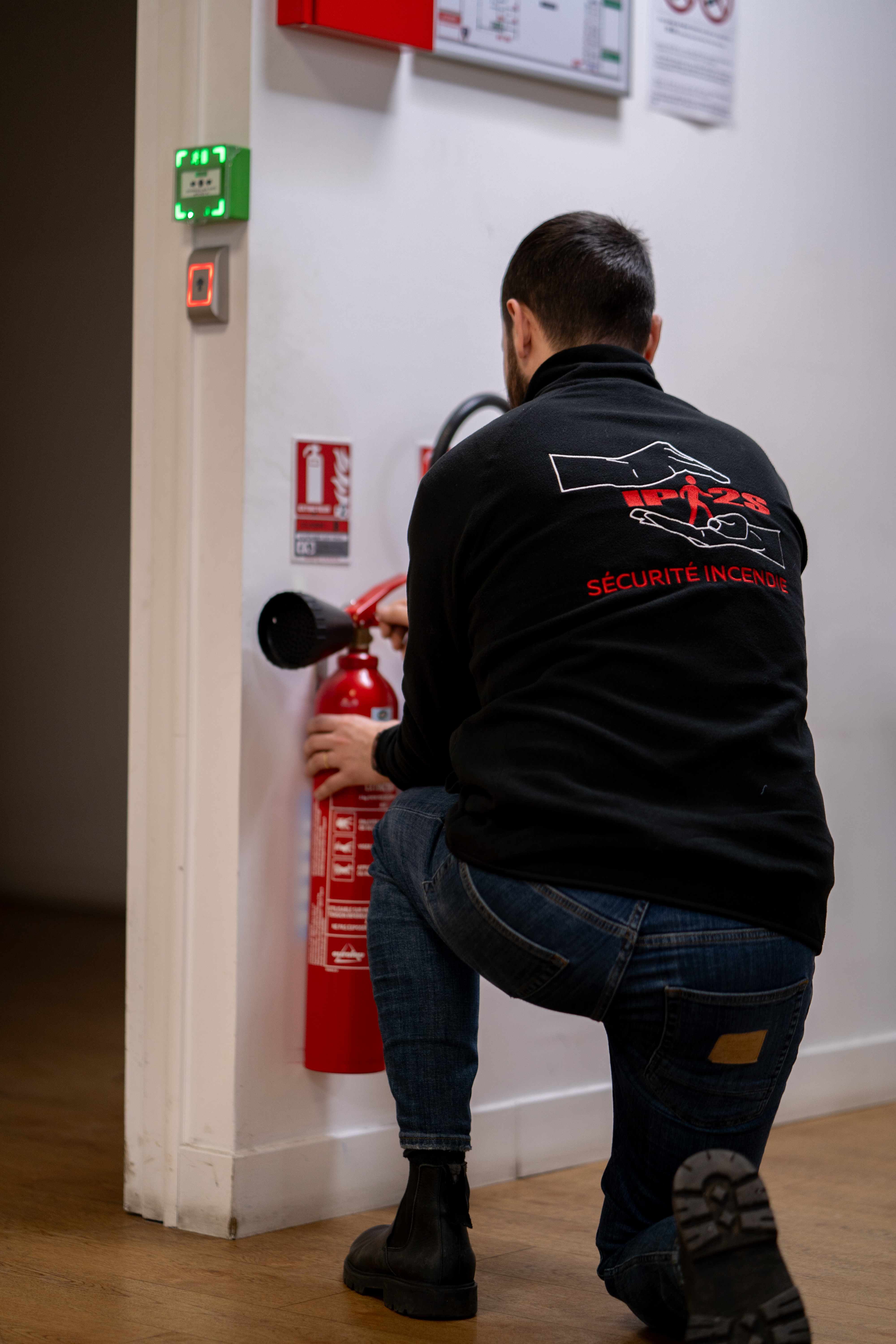 Technicien installant un extincteur mural